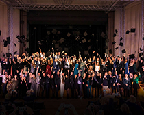 Absolventen werfen einen Absolventenhut in die Luft Absolventen werfen einen Absolventenhut in die Luft